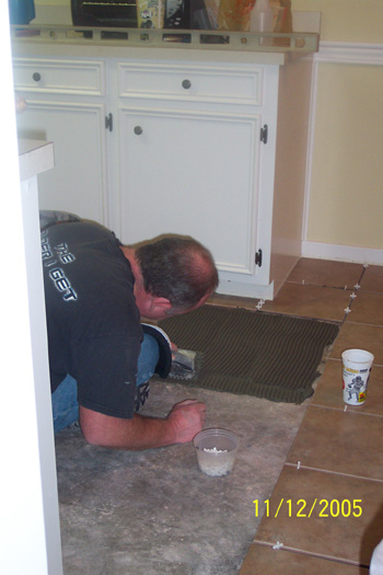 Terry laying tile in the kitchen